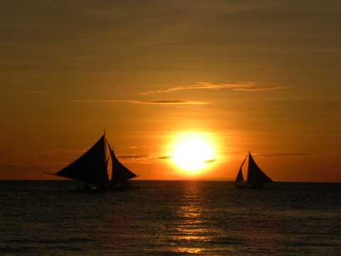 夕阳下的海上帆船剪影